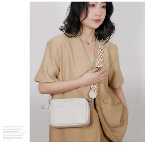 Detail of off-white lychee grain leather camera bag with wide colorful shoulder strap