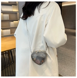 Fashionable silver heart-shaped metal mesh bag with chain strap worn on white blazer