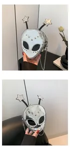 Detail shot of a silver alien-shaped crossbody bag with star antennas and a metal chain