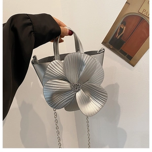 Detailed close-up of a silver bucket bag featuring a large 3D metallic floral design
