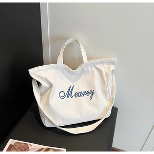 Détail du sac cabas en toile blanche avec broderie bleue et large bandoulière réglable
