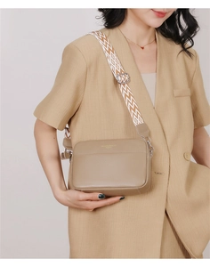 Detail of khaki pebbled leather crossbody bag with wide geometric wave strap and gold logo