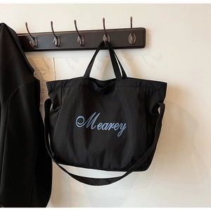 Détail d'un grand sac fourre-tout noir en toile suspendu avec lettrage artistique bleu