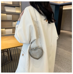 Close-up of heart-shaped silver mesh chain bag styled with a cream-colored coat