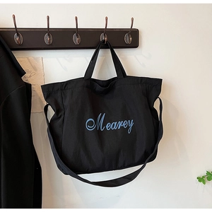 Détail d'un sac cabas noir suspendu au crochet avec impression texte Mearey bleu
