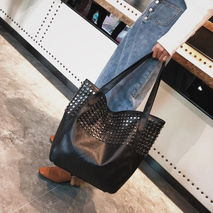 Grande borsa tote nera con borchie argentate e doppi manici indossata da una modella