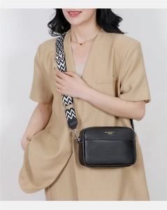 Detailed view of black litchi pattern leather crossbody bag with geometric woven strap