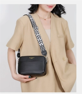 Detail of black pebbled leather crossbody bag with geometric wide strap and gold logo