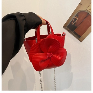 Detail of red bucket bag featuring 3D floral petals and silver metal chain strap