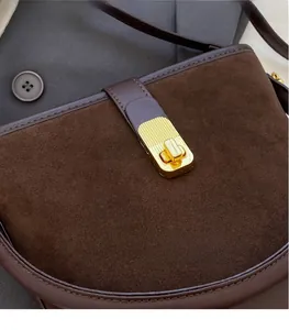 Detailed close-up of retro brown bucket bag with gold metal lock and suede texture