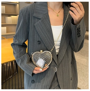 Close-up of golden heart-shaped mesh crossbody bag on a grey striped blazer