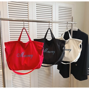 Trois sacs cabas en toile de couleurs rouge, noir et blanc avec lettrage Mearey