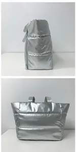 Détail du sac de voyage matelassé argenté avec finition métallique et poche à fermeture