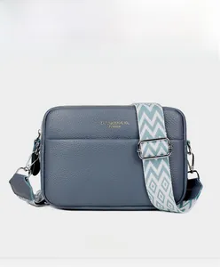 Close-up of navy pebbled leather camera bag with a stylish blue-white geometric wide strap