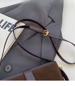 Detail of adjustable leather strap and gold buckle on a brown vintage bucket bag