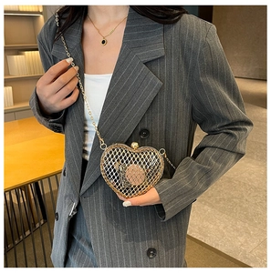 Detail of golden heart-shaped metal mesh chain bag with intricate woven texture