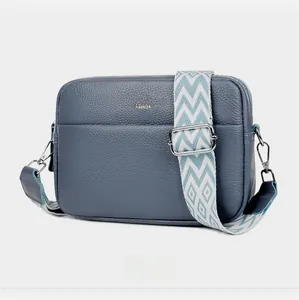 Detail view of blue lychee grain leather crossbody bag with colorful woven strap