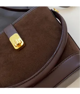 Detail of dark brown matte suede shoulder bag with retro golden rectangular metal lock