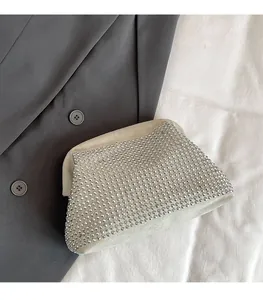 Detailed view of beige suede clutch bag featuring luxury silver rivet embellishments