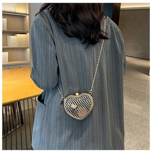 Detailed view of heart-shaped hollow metal crossbody bag with fine gold mesh and chain strap
