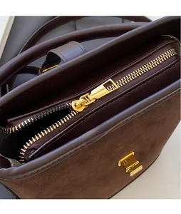Close-up of golden hardware zipper and suede texture on dark brown bucket bag