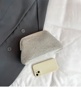 Top view of a silver rhinestone cloud clutch bag on a grey blazer showing size scale