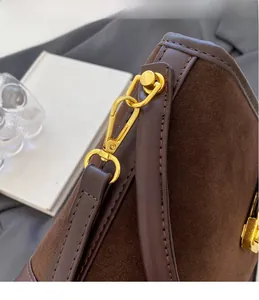 Detail of dark brown suede bucket bag featuring high-gloss gold hardware hooks and trim