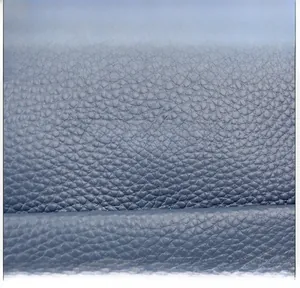 Macro view of blue litchi pattern leather with gold branded logo and fine texture
