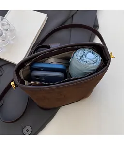 Detail view of the large capacity interior of a brown bucket bag holding a phone and umbrella
