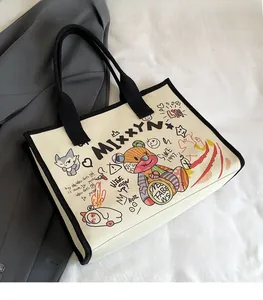 Close-up of canvas tote bag featuring artistic cat and bear prints with black handles