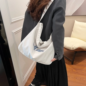 Grand sac cabas en toile blanche avec texte bleu porté par un mannequin en intérieur