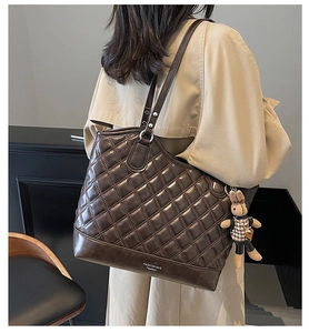 Detail of dark brown quilted tote bag with fashion tag and bunny doll charm