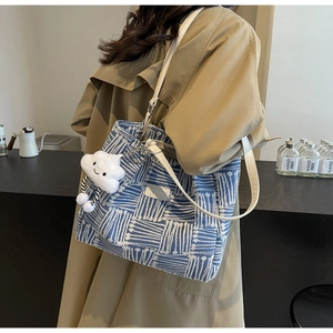 Detalle del bolso tote de lona tejida azul y blanca con correa de cuero y adorno