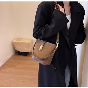 Side view of dark brown bucket bag featuring matte texture and golden twist lock detail