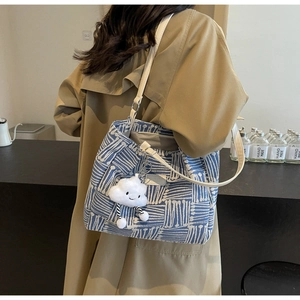 Detalle del bolso tote de lona con patrón geométrico azul y colgante de nube suave