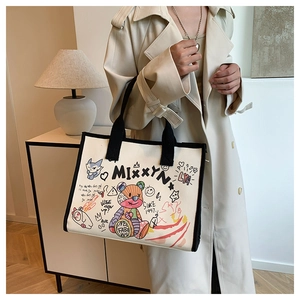 Detailed shot of large cream canvas tote with colorful street graffiti and black handles