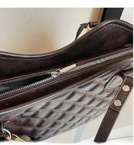Close-up of smooth metal zipper and diamond-quilted texture on dark brown bucket bag