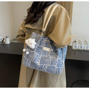 Bolso tote tejido azul con correas blancas y colgante de nube de felpa en escena real
