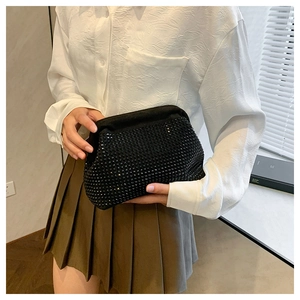 Detail of a trapezoid evening clutch bag with black rhinestones held by a model