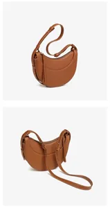 Detail of brown textured leather crescent bag with contrast white stitching and metal zipper