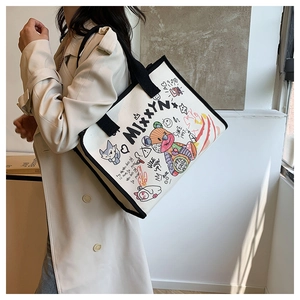 Detail of white canvas tote bag featuring bear and graffiti prints worn by a model