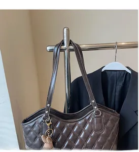 Detail of dark brown quilted tote bag showing fine leather texture and plush bear charm