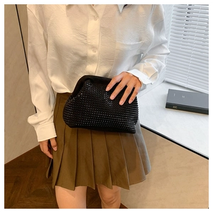 Detail of a black sparkling rhinestone clutch bag paired with a green pleated skirt