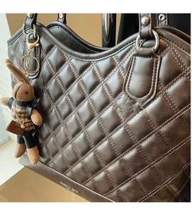 Detail of dark brown quilted tote bag with a decorative bunny charm and silver rings