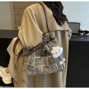 Detalle del bolso tote de tejido geométrico con correas de cuero marrón y colgante nube