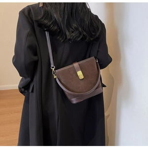 Detail shot of a brown suede bucket bag with gold buckle on a model's back