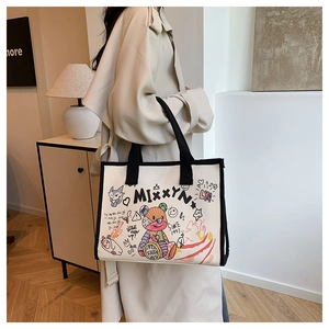 Detail of beige canvas tote bag with colorful graffiti and black webbing handle for daily use