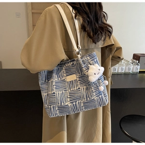 Detalle del bolso tote tejido en azul y blanco con correa blanca y colgante de nube