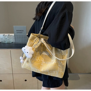 Detalle del bolso tote amarillo con textura de punto y colgante de nube blanca
