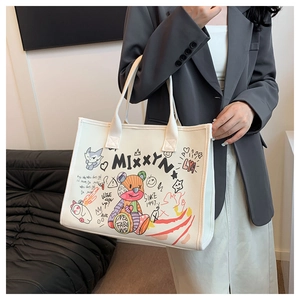 Close-up of large canvas tote bag featuring colorful graffiti prints and sturdy handles